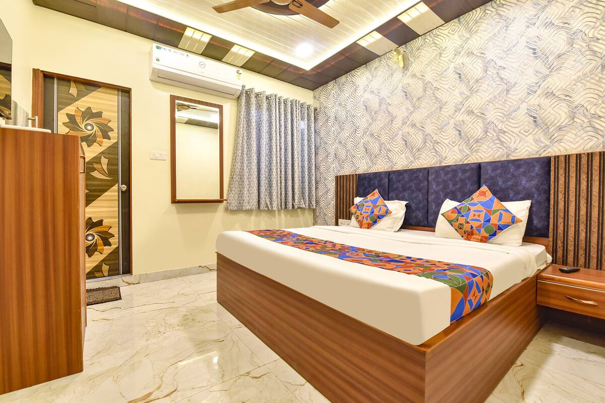A bedroom with a large bed, wooden headboard, and a patterned wall.