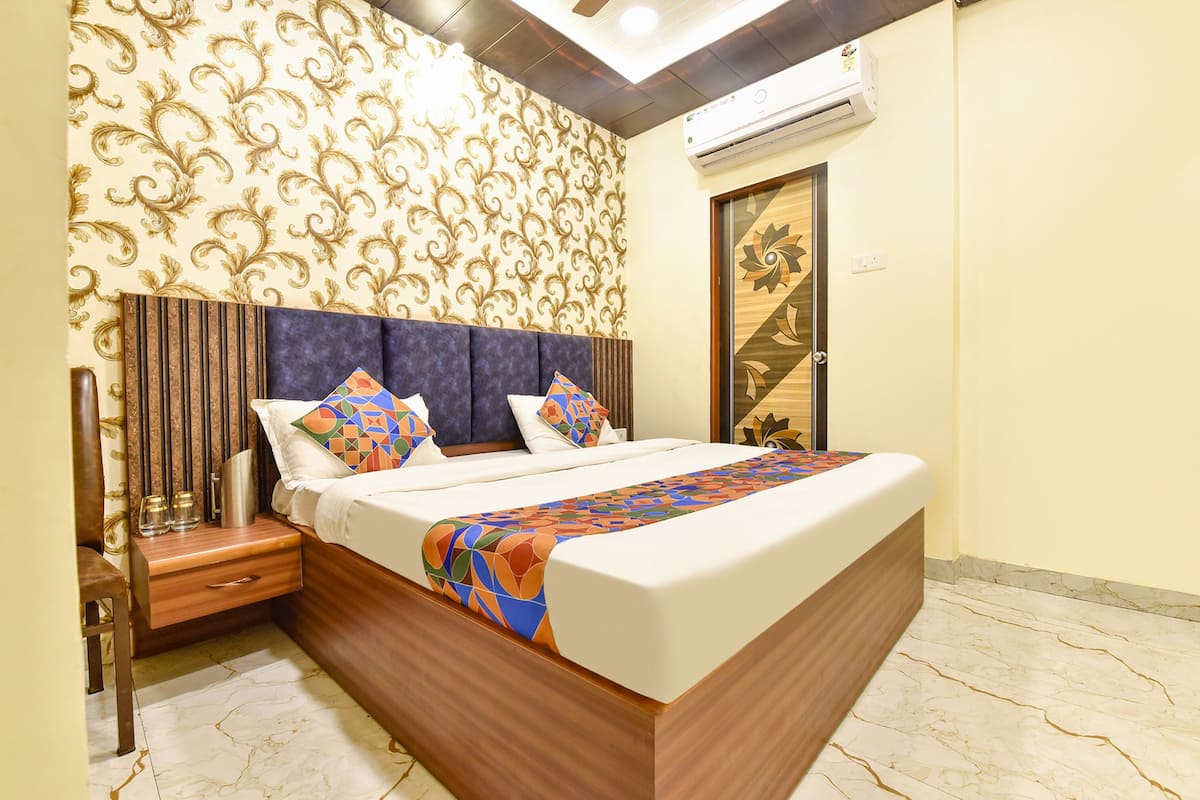 A modern bedroom with a large bed, a nightstand, a decorative wall, and an air conditioning unit.