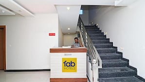 A reception desk with a sign for 'fab hotels' and a staircase leading to an upper floor. - Fabexpress Green Comfort (Dehradun)