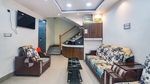 A modern living room with a sofa, a coffee table, and a TV mounted on the wall. - Fabhotel Raj Niwas (Patna)