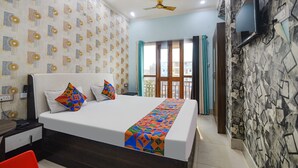 A hotel room with a bed, a TV, a ceiling fan, and a window with curtains. - Fabhotel Raj Niwas (Patna)