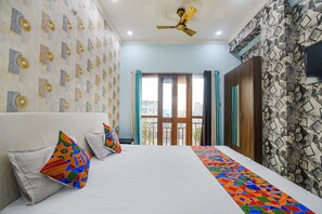A hotel room with a bed, colorful pillows, a ceiling fan, and patterned walls. - Fabhotel Raj Niwas (Patna)
