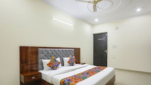 A neatly made bed with a wooden headboard, white bedding, and colorful pillows.