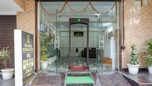 The entrance to The Royal Residency Inn with a marble floor, a glass door, and a sign indicating PG A/C rooms available.
