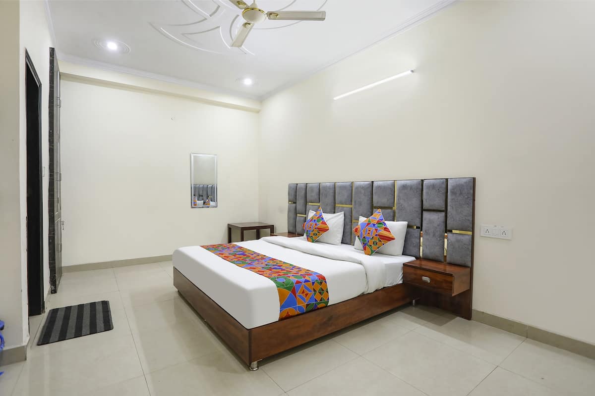 A bedroom with a large bed, a nightstand, a bedside table, a ceiling fan, and a wall-mounted mirror.