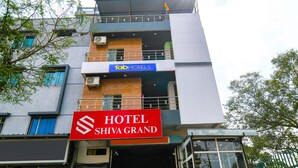 A multi-story hotel with a prominent red sign for 'Hotel Shiva Grand' and a blue sign for 'Tab Hotels'.