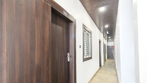 A hallway with wooden doors, a window with bars, and a tiled floor.