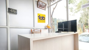 A reception desk with a television, a chair, and a small statue.
