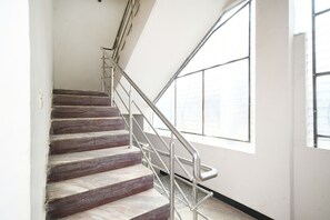 Una escalera con barandillas metálicas y ventanas amplias.