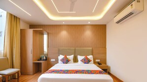 Ein Hotelzimmer mit Bett, Nachttischen, Schreibtisch, Stuhl und Klimaanlage.