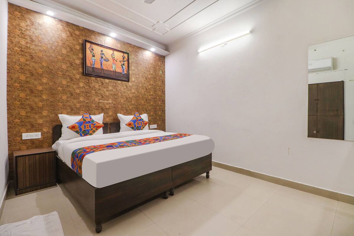 A neatly arranged bedroom with a bed, nightstand, and a wall-mounted air conditioning unit.