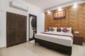A bedroom with a bed, wardrobe, and artwork on the wall. - Fabexpress Rainbow Villa (New Delhi)