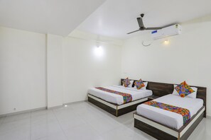 A hotel room with two beds, a ceiling fan, and an air conditioning unit. - Fabexpress Park View (Hingna)