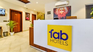 Un espace d’accueil d’hôtel comprenant un comptoir de réception, un téléviseur et un panneau indiquant « Fab Hotels ».