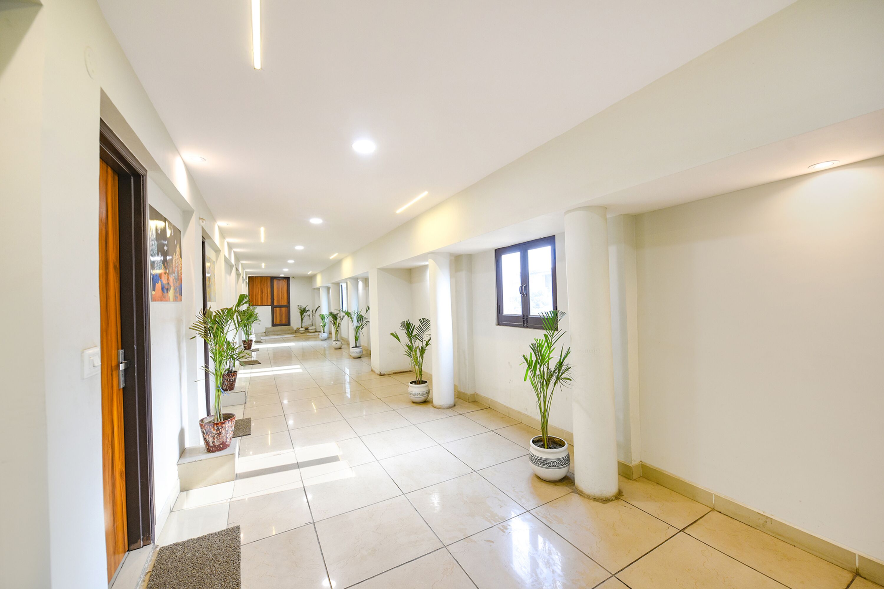 Un hall d’entrée spacieux et bien éclairé, doté de carreaux au sol, de plantes en pot et d’un design moderne.