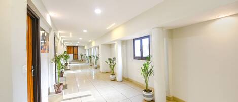 Un hall d’entrée spacieux et bien éclairé, doté de carreaux au sol, de plantes en pot et d’un design moderne.