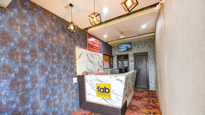 A hotel reception area with a marble counter, patterned walls, and a television screen.
