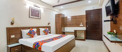 A hotel room with a bed, bedside tables, a wardrobe, a mirror, a TV, and a ceiling fan.
