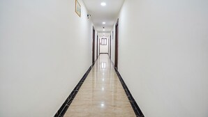 A long, narrow hallway with white walls and a shiny, reflective floor.