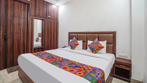 A bedroom with a large bed, a wooden wardrobe, and a nightstand.