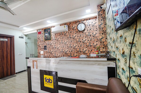 A hotel reception area with a marble counter, a clock, and a wall decorated with stacked logs.