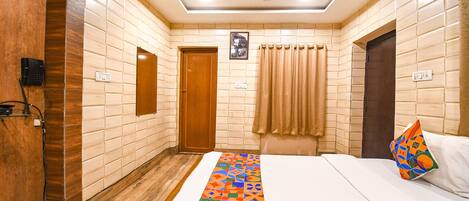 A hotel room with a bed, a ceiling fan, a wooden door, and a wall with a geometric patterned runner.