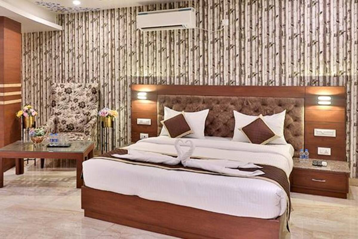 A hotel room with a large bed, a bedside table, a chair, a desk, and a decorative wall.