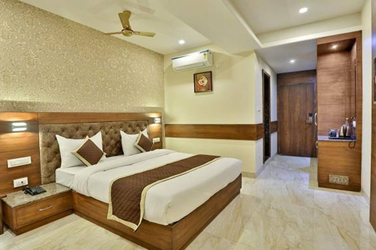 A bedroom with a large bed, wooden headboard, bedside tables, an air conditioning unit, and a ceiling fan.