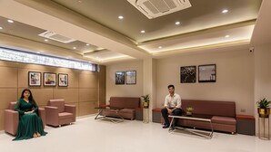 A modern waiting area with two sofas, a coffee table, and framed pictures on the walls. - FabHotel Orange Oasis (Bhopal)