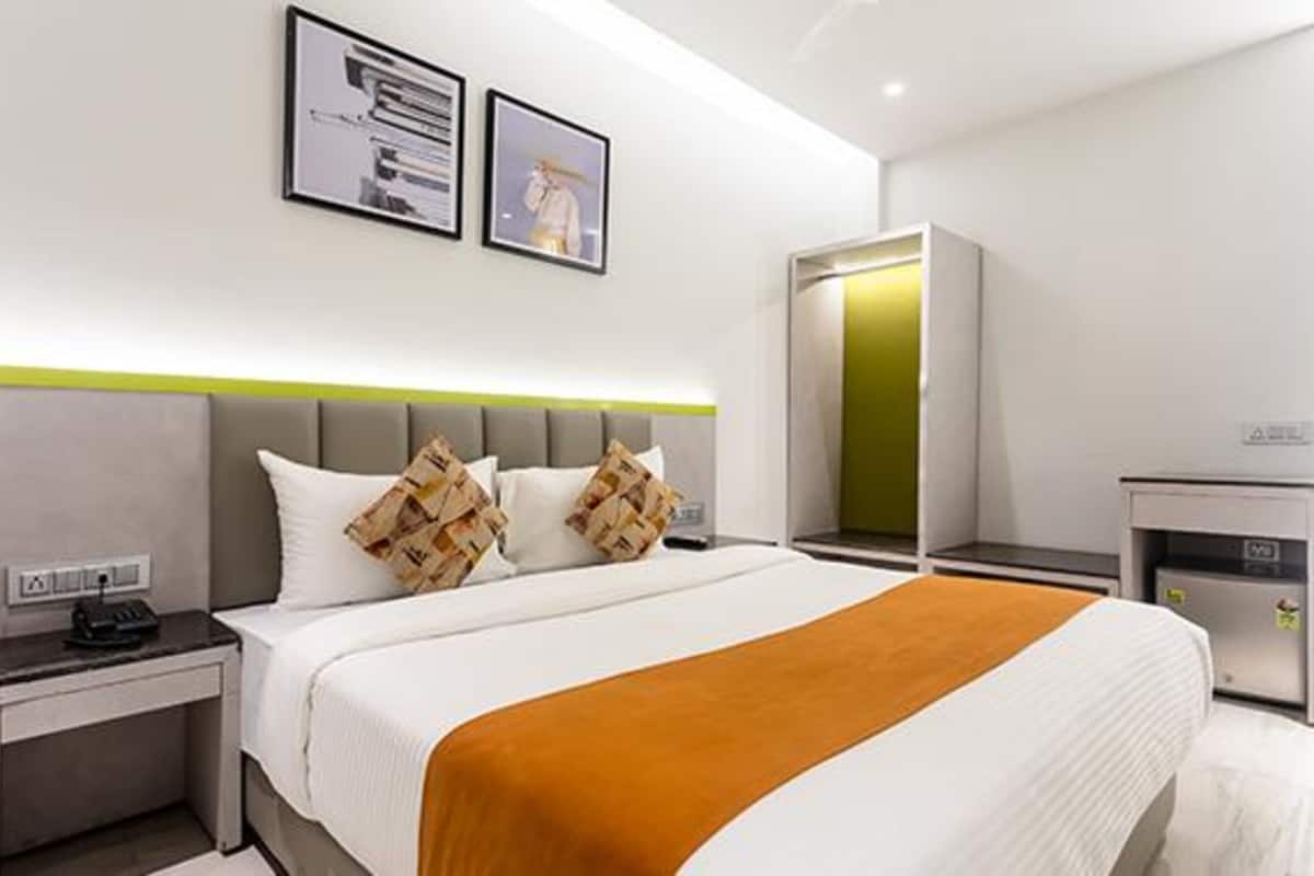 Een moderne hotelkamer met een groot bed, nachtkastje, garderobe en spiegel.