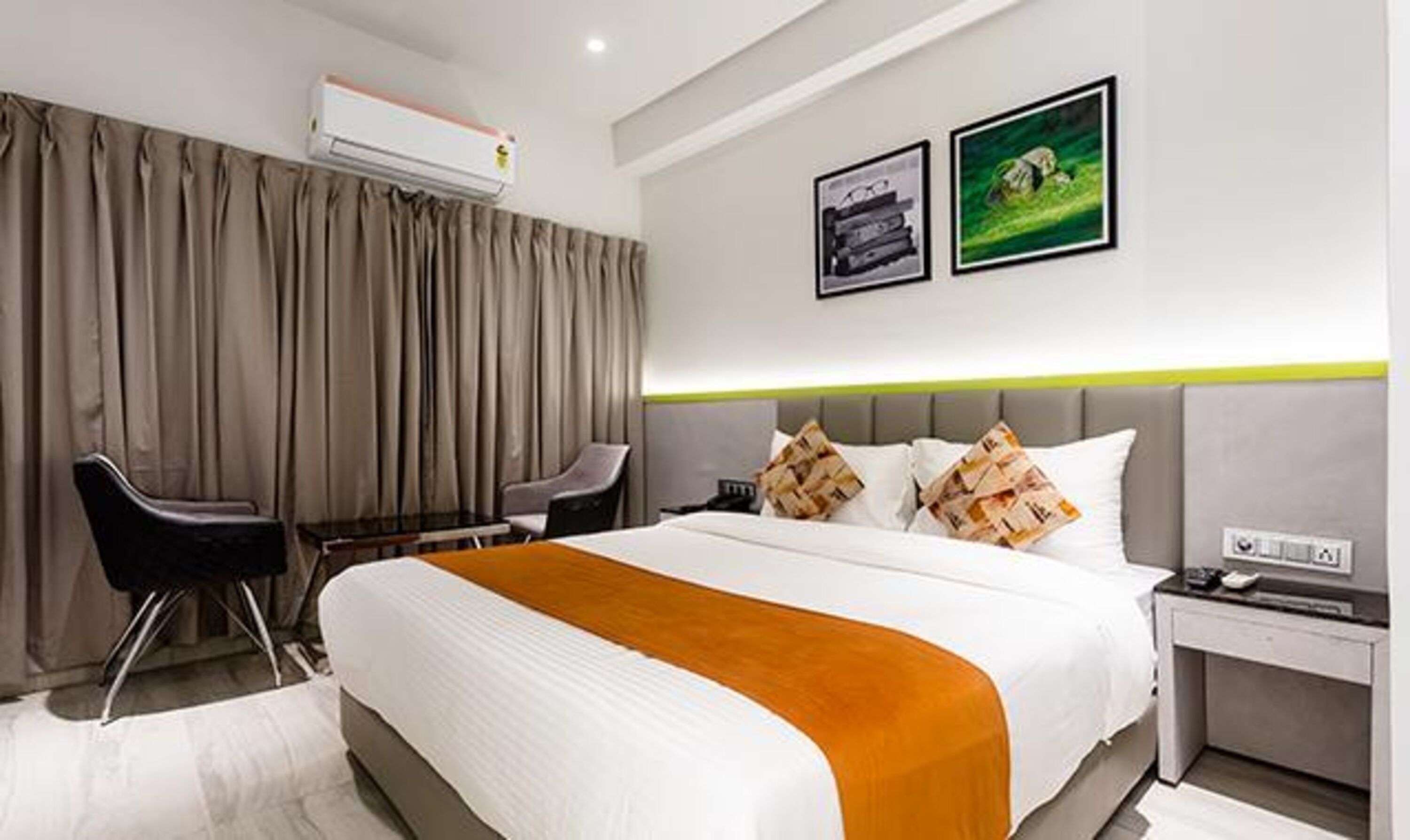 A modern hotel room with a large bed, a desk, and two chairs.