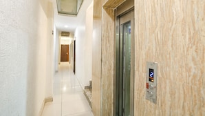 Un pasillo moderno con pared de mármol, un ascensor y una pantalla digital que muestra el número 2.