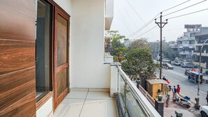 A balcony with a view of a busy street, a small shop, and a building with a sign. - Fabhotel Apple Pie (Noida)
