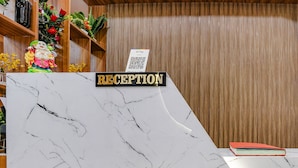 A reception desk with a marble top and a wooden panel design. - Fabhotel Max (Vadodara)