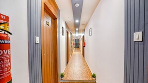A hallway with wooden doors, a fire extinguisher, and a sign on the wall. - Fabhotel Max (Vadodara)