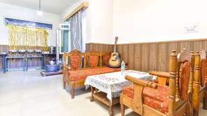 A dining area with wooden furniture, a guitar, and a table with a lace tablecloth. - Fabhotel Elavali Valley (Manali)