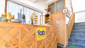 A reception desk with a 'fab hotels' sign, a staircase, and a window with patterned curtains. - Fabhotel Elavali Valley (Manali)