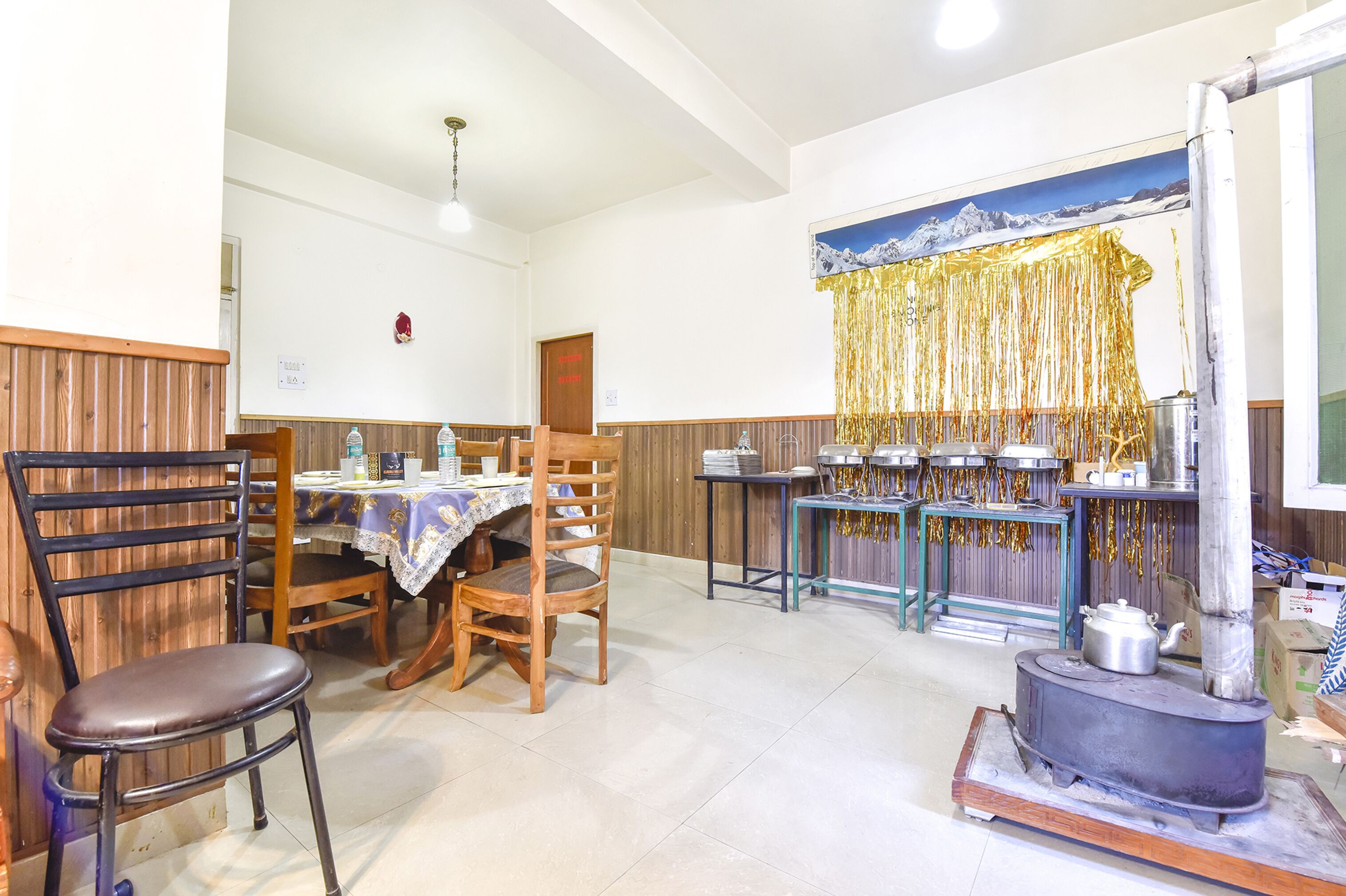 Un comedor con sillas de madera, una mesa con mantel y una mesa de buffet con recipientes de comida.