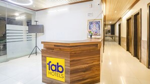 A hotel reception desk with a wooden finish and a 'fab hotels' sign. - Fabhotel Green Valley I (Dindori)