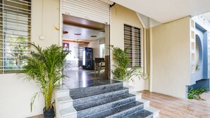 A modern interior with a staircase leading to a living area, featuring a large window, potted plants, and a ceiling fan. - Fabhotel Green Valley I (Dindori)