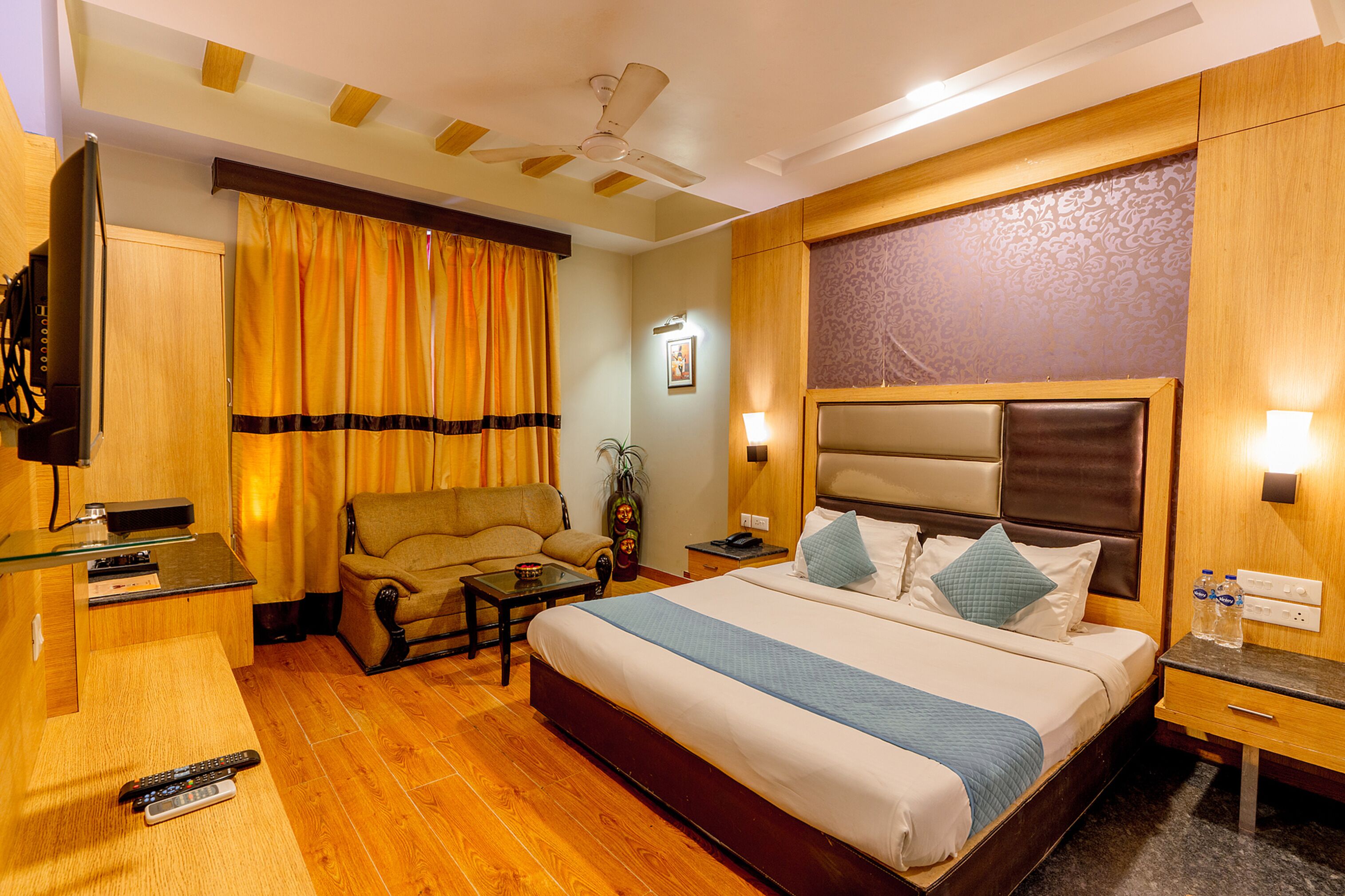 A hotel room with a bed, a sofa, a desk, and a television.