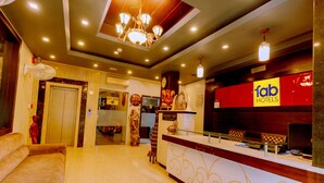 A hotel reception area with a reception desk, a clock, and a gift shop sign. - Fabhotel Prime Aroma Residency (Jaipur)