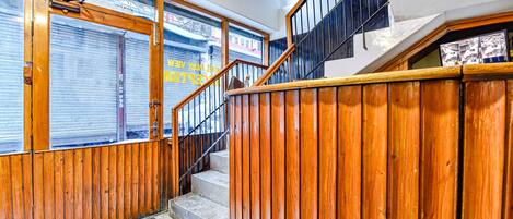 A wooden staircase with a metal railing leading to an upper floor.