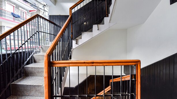 A staircase with black railings and wooden handrails, leading to an upper floor. - Fabhotel Park View I (Manali)