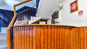 A reception area with a wooden counter, a staircase, and a wall-mounted sign. - Fabhotel Park View I (Manali)