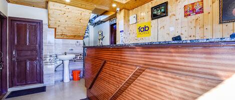 A wooden reception desk with a 'fab hotels' sign, a clock, and a small statue.