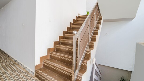 A staircase with wooden steps and metal railings, leading to an upper floor. - Fabexpress Anmol'S Peace Home Stay (Ootacamund)