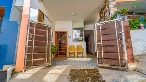 A residential entrance with two open metal gates, a number '54' on the wall, and two wooden chairs outside. - Fabexpress Anmol'S Peace Home Stay (Ootacamund)