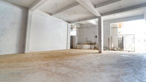 A spacious, unfinished interior with concrete walls and floors, large pillars, and a visible staircase leading to an upper level. - Fabexpress Anmol'S Peace Home Stay (Ootacamund)