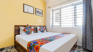 A hotel room with a bed, a window with blinds, and two framed pictures on the wall. - Fabexpress Anmol'S Peace Home Stay (Ootacamund)